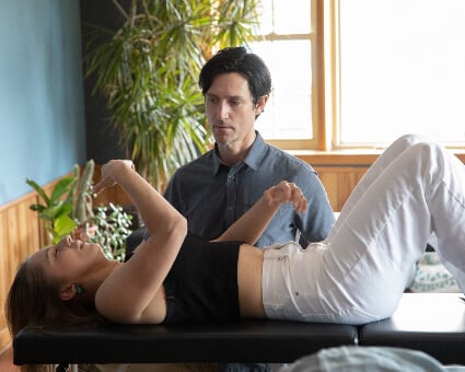 A man performs a chiropractic adjustment on a woman lying on a treatment table.